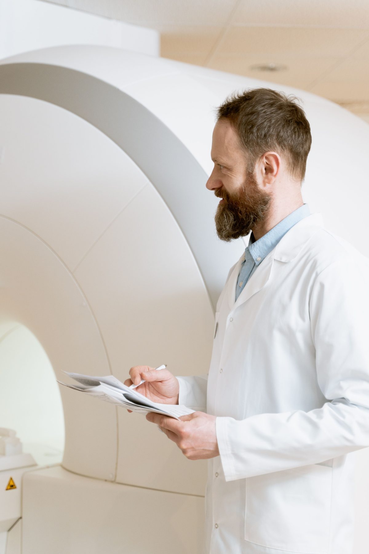 A radiologist reviewing paperwork beside an MRI scanner