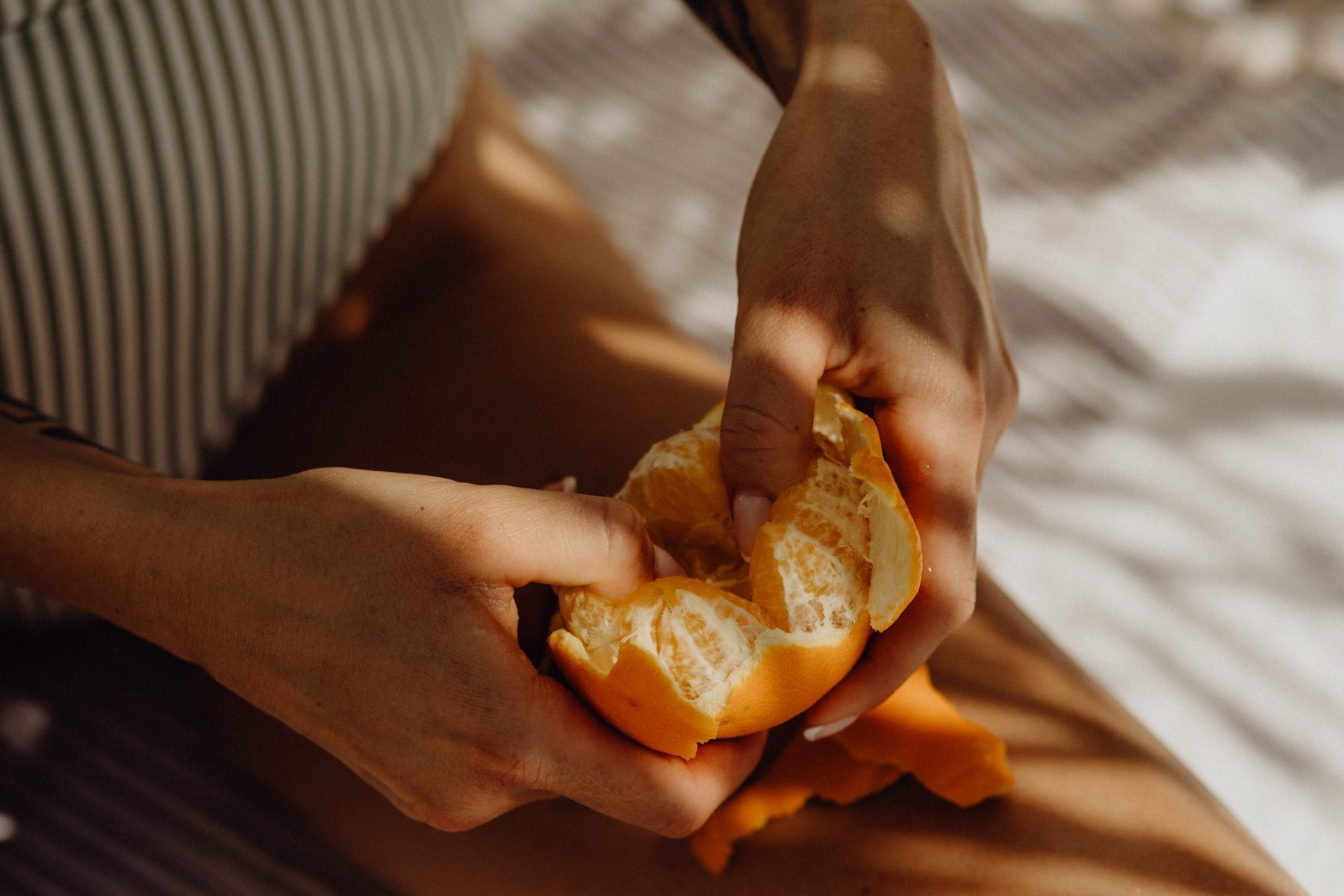 Hands peeling a fresh orange in warm light